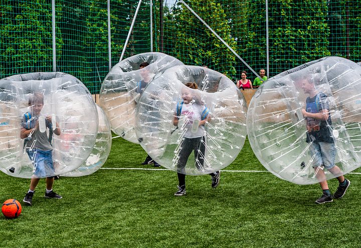 Kids running in bubbles on the pitch, ball at their feet